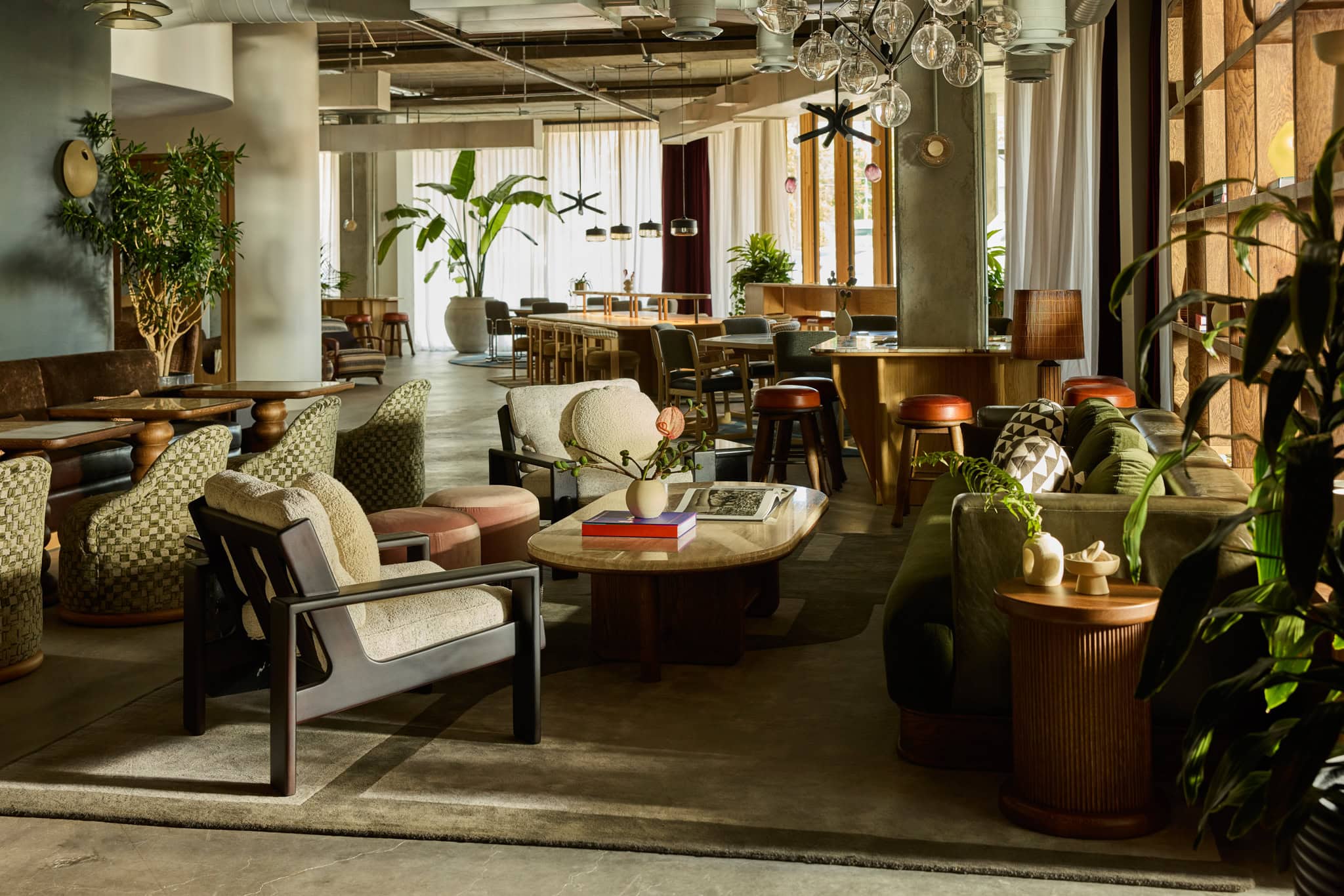 The Malin East Austin luxurious lounge with eclectic furniture, lush plants, globe chandeliers, and warm earthy tones