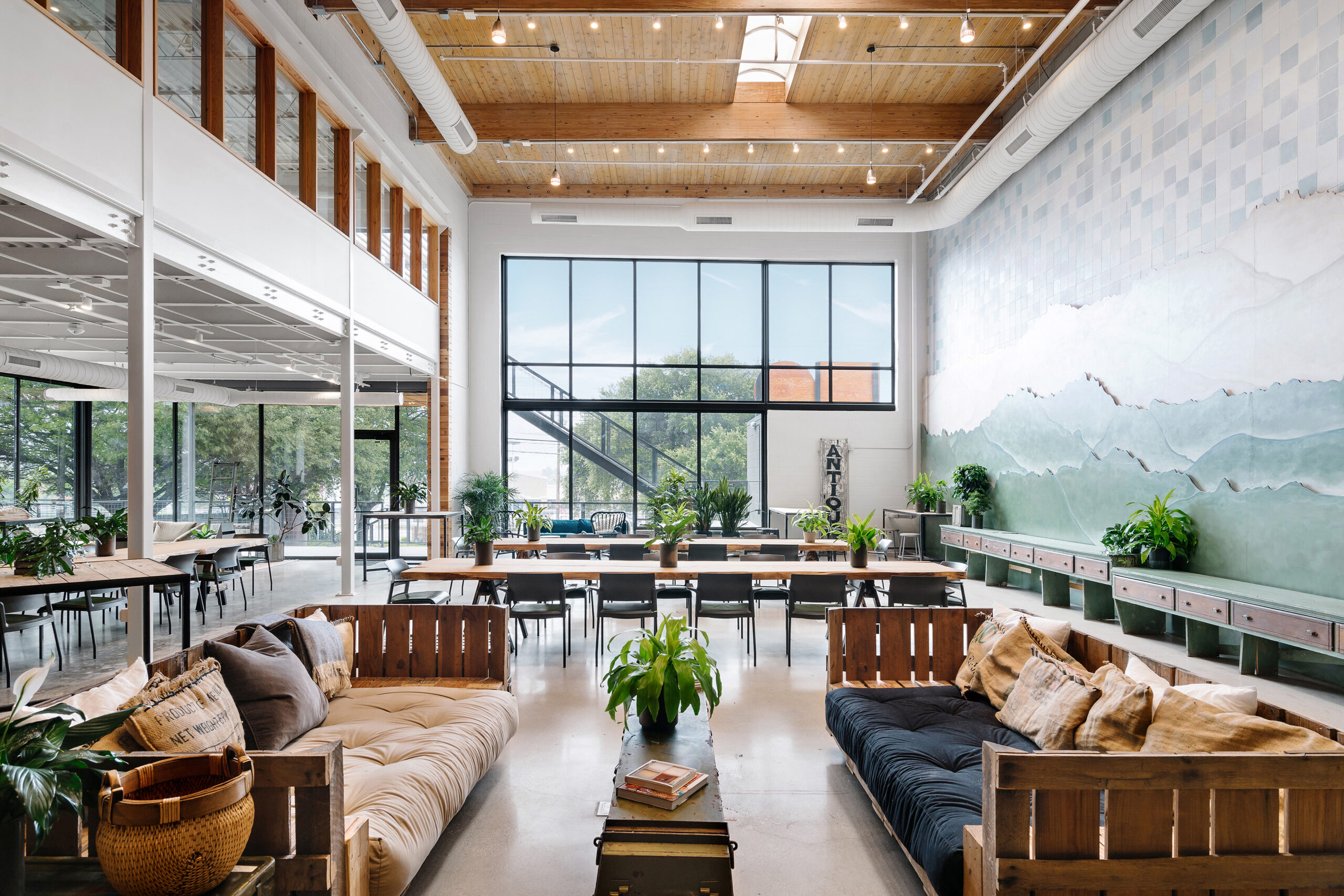 Vuka North Loop coworking and event space with rustic wooden furniture, plants, and mountain mural