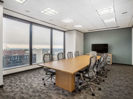 Regus Energy Centre boardroom with long wood table, mesh office chairs, large windows with city skyline view, and sage green accent wall